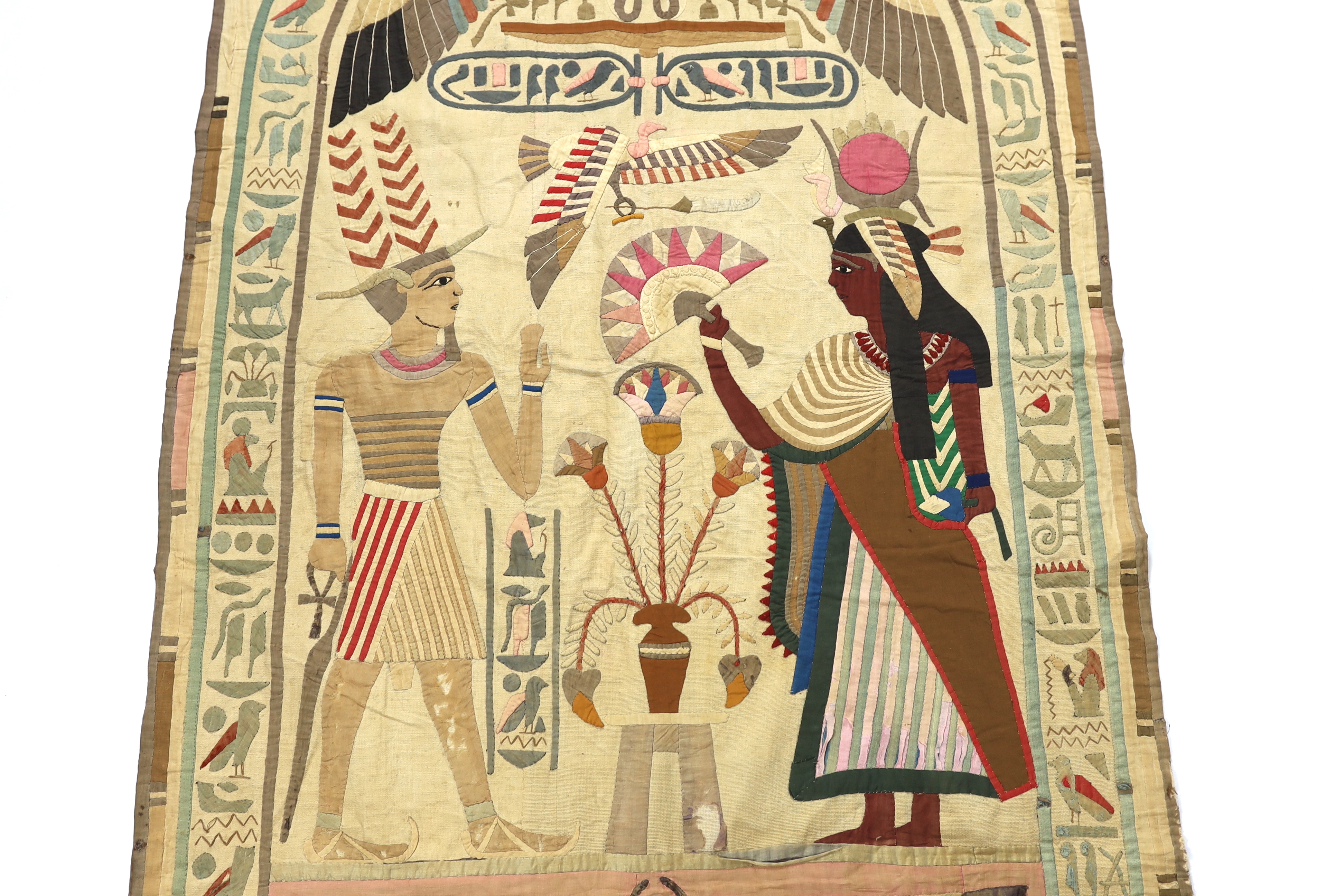 A 1930’s large Egyptian appliqué wall hanging, depicting Wadjet, (Goddess and protector of Kings) and Amun (God of wind) surrounded by hieroglyphic decorative symbols, 134cm wide x 268cm long